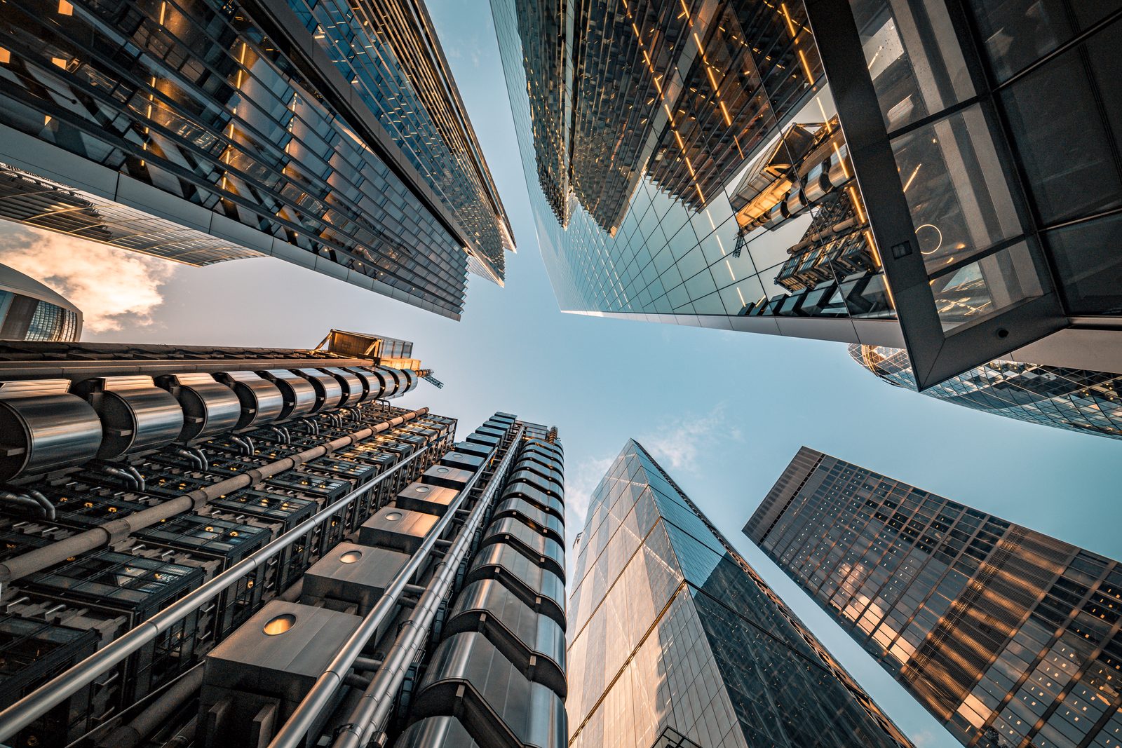 Looking straight up between the towers of the City of London, glass and exposed steel converging on a patch of sky.