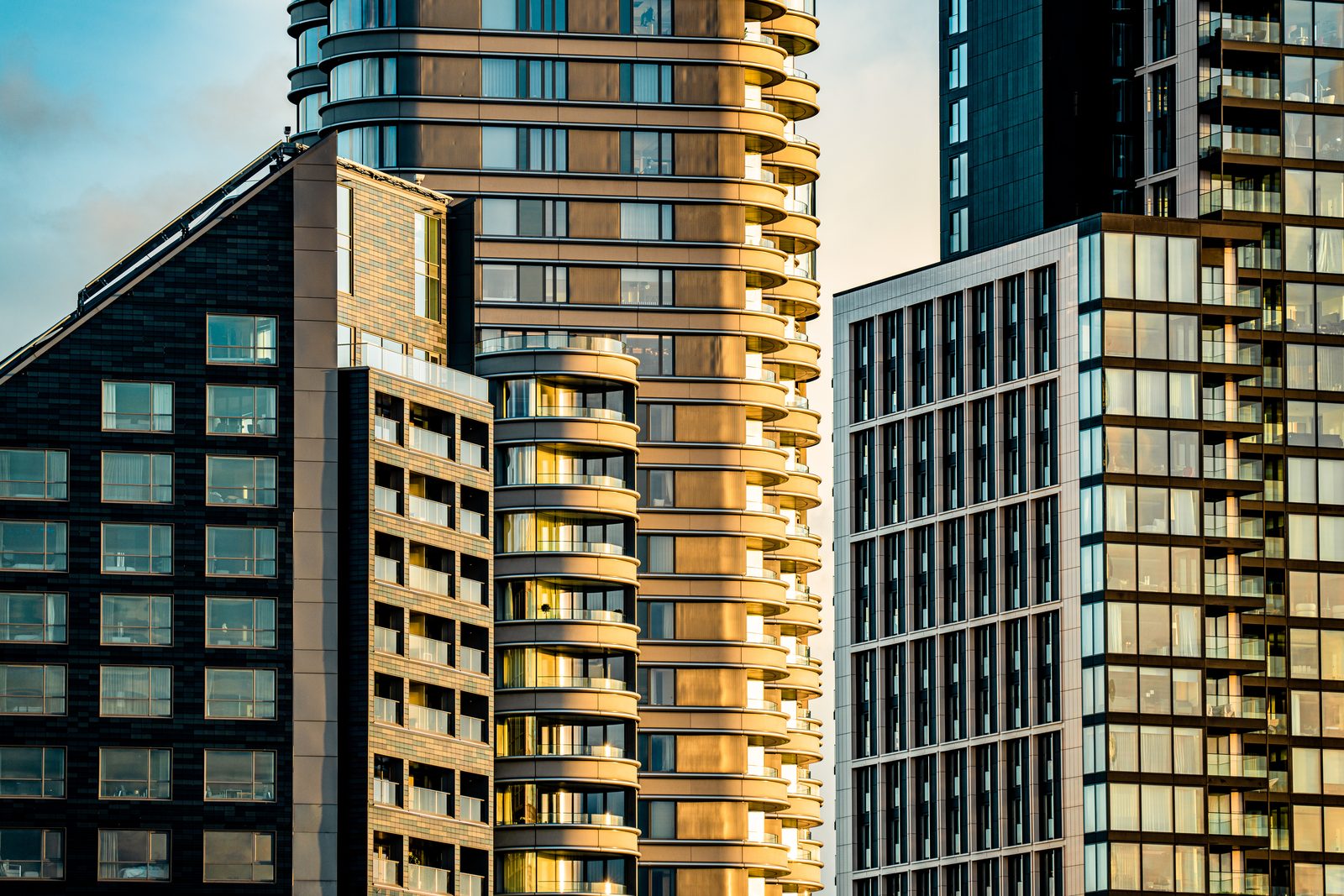 Several occupied residential towers standing close together, curved balconies and windows catching low evening light.